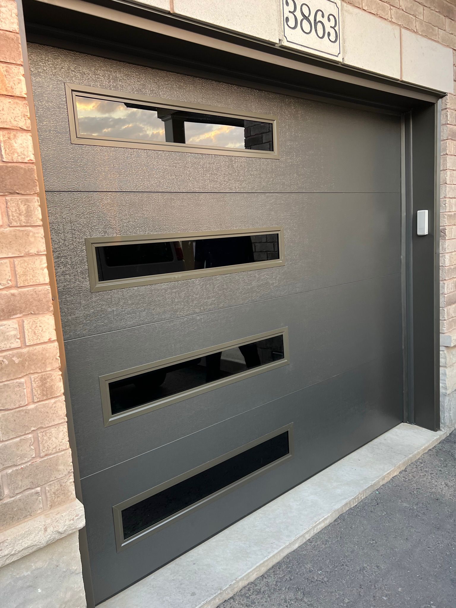 Charcoal contemporary garage door at house 3863 photographed at dusk in warm golden-hour light