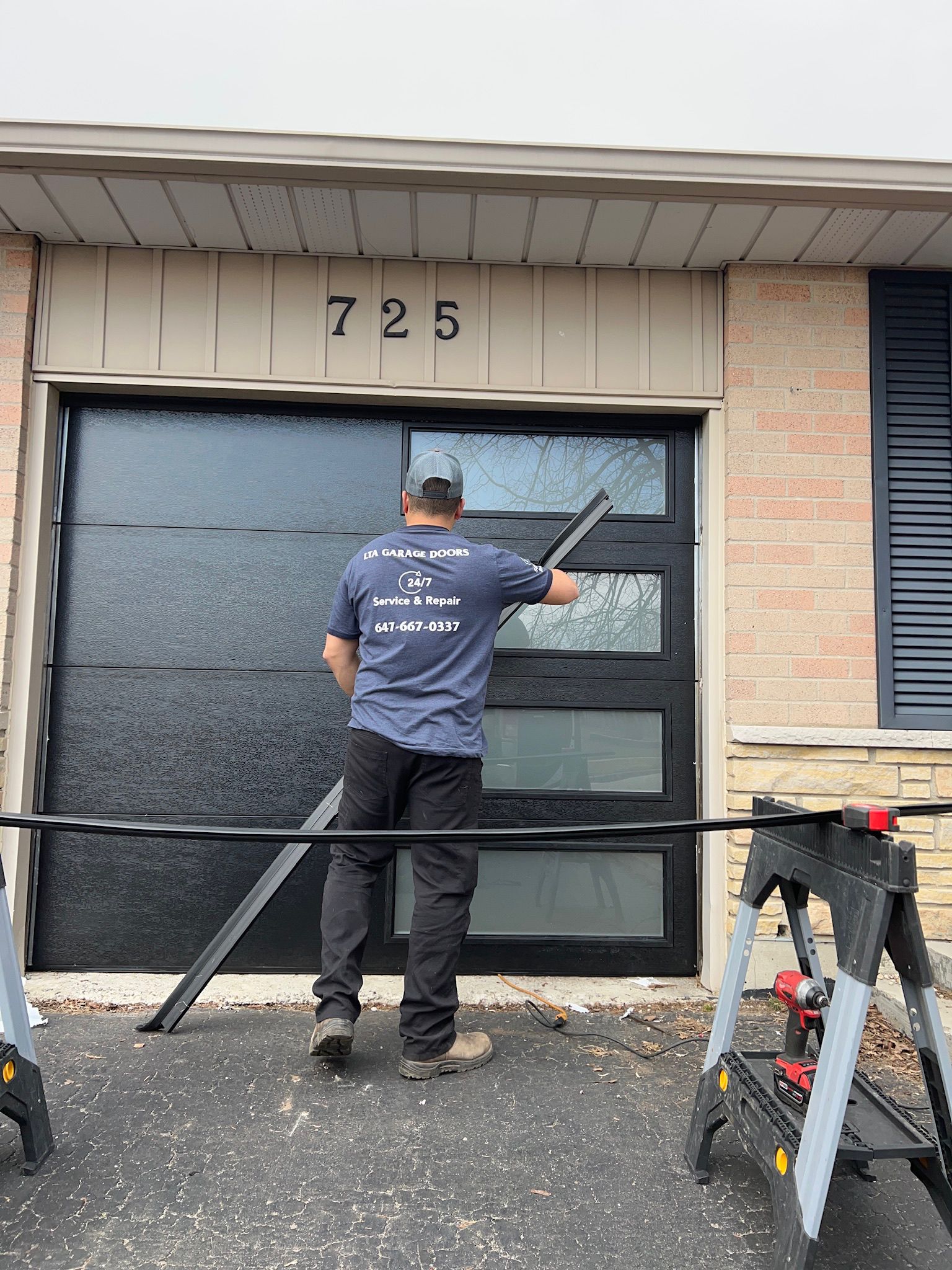 LTA Garage Doors technician installing a large contemporary garage door at a commercial-style property on house 725